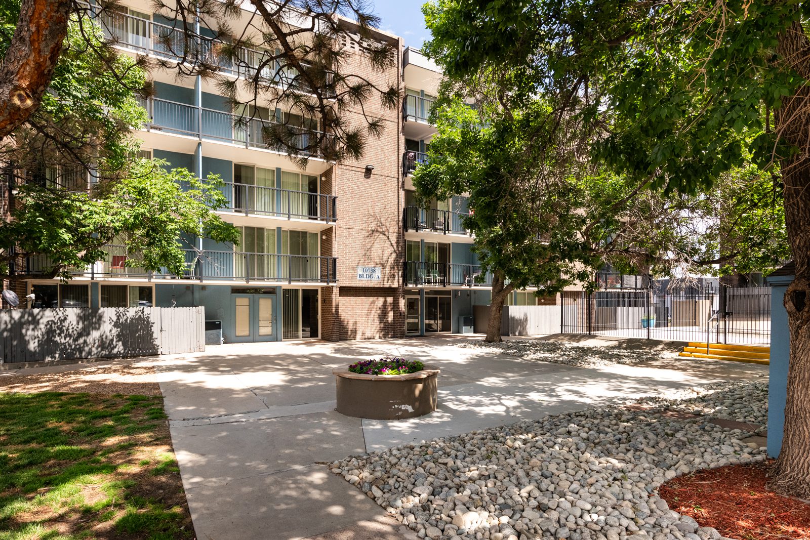 Apartment courtyard with large trees and landscaping.