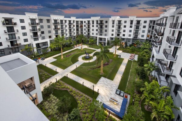 Courtyard with paver walkways, lush lawns, and palm trees.