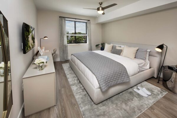 Bedroom with plush bed, bedside tables with lamps, and large windows.