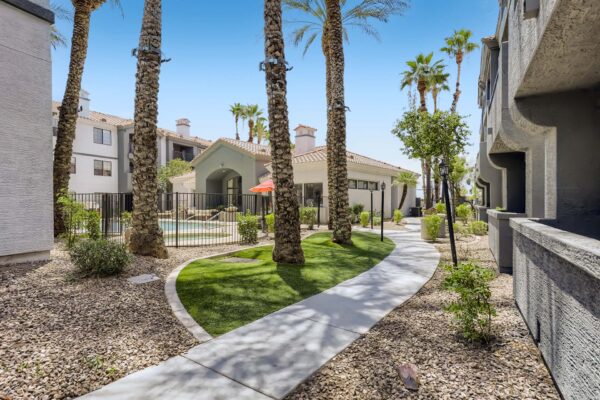 Mandarina apartments courtyard with lush landscaping, paved walkways, and tall palm trees.