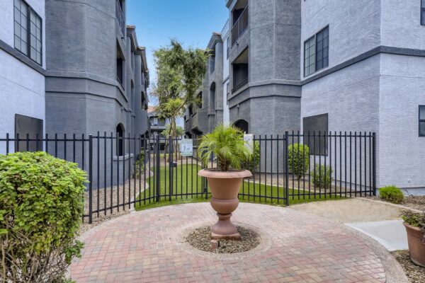 Mandarina apartments dog park with metal fence and lush landscaping.