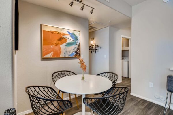 Mandarina apartment dining area with round dining table, metal chairs, and large artwork.
