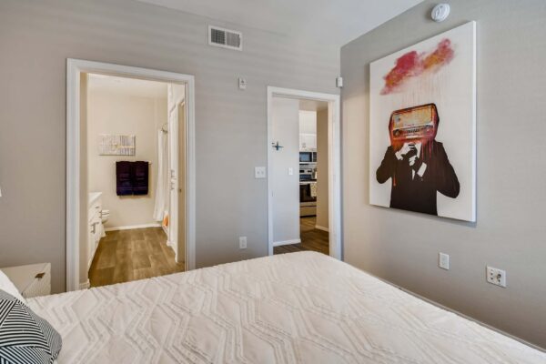 Mandarina apartment bedroom with large bed, artwork, and doors to living and bathroom.