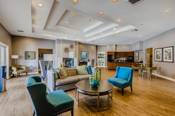 Pavilions at Arrowhead apartments clubroom with plush seating, fireplace, and community kitchen.