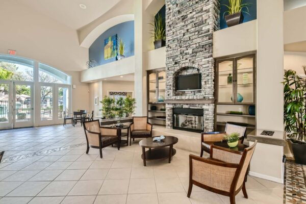 Springs at Alta Mesa apartments lobby with stone fireplace, seating area, and shelves with decor.