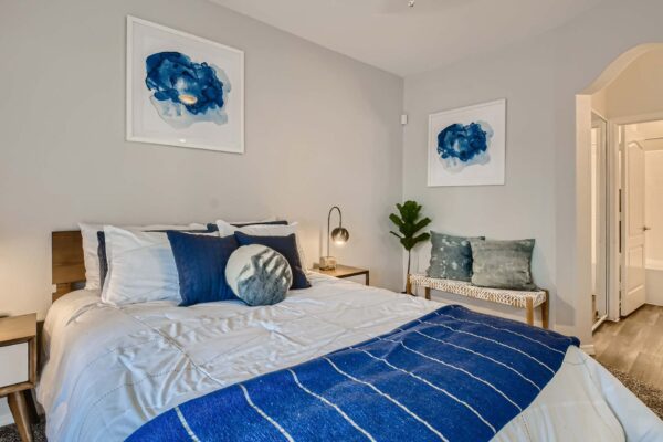 Springs at Alta Mesa apartment bedroom with wood bed, bedside tables with lamps, and abstract artwork.