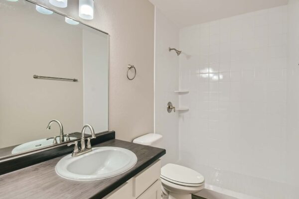 Tempe Vista apartment bathroom with white cabinets, dark counters, and tiled shower.
