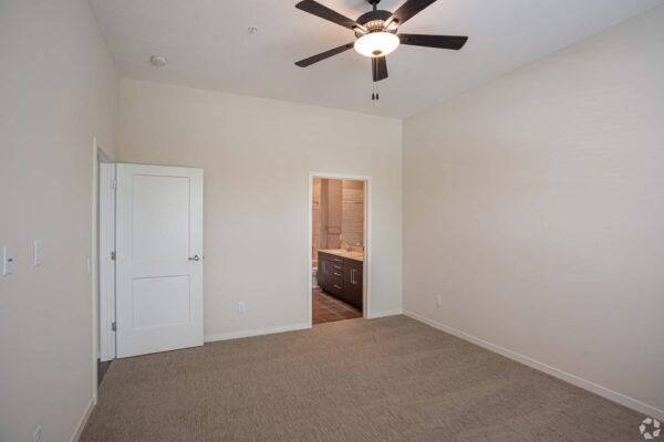 The Locale apartment bedroom with carpet and ceiling fan.