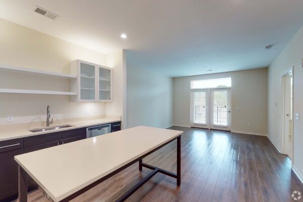 The Locale apartment living area with wood style floor, modern kitchen, and balcony door.