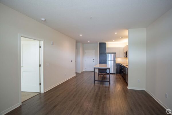 The Locale apartment living area with wood style floor and modern kitchen with island table.