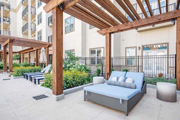 The Locale apartments pool area with daybeds and wood pergolas.