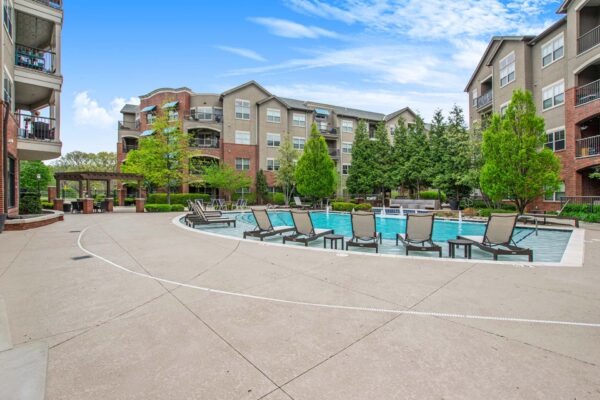 Village at Mission Farms apartments pool area with lounge chairs and pergola.