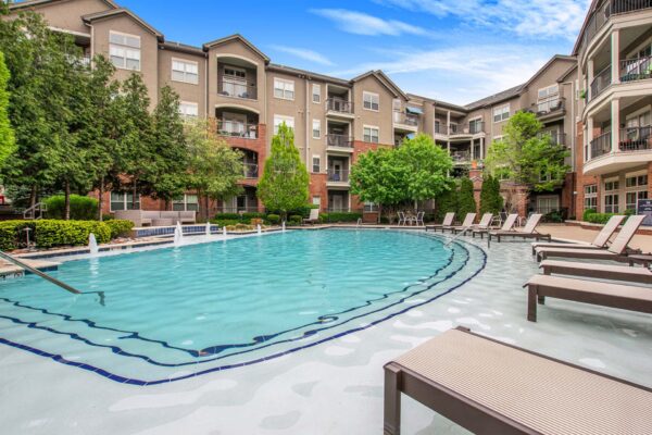 Village at Mission Farms apartments pool area with lounge chairs and fountains.