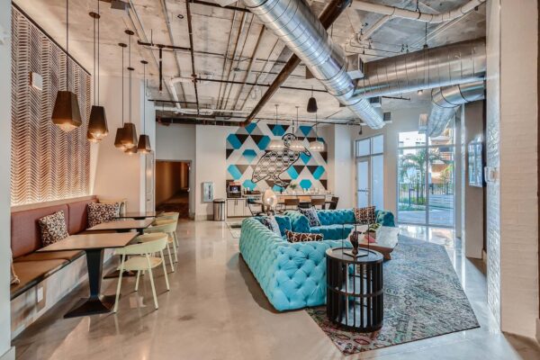 Arte St. Pete apartments lounge with plush couch, dining booths, and coffee bar.