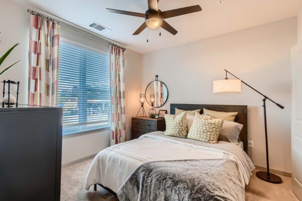 Arte St. Pete apartment bedroom with carpet, plush bed with headboard, ceiling fan, and large window.