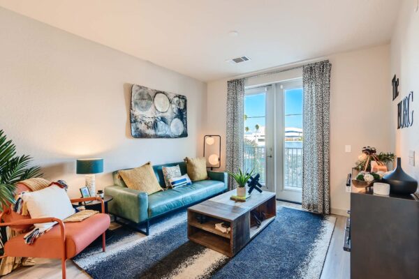 Arte St. Pete apartment living room with plush seating, large artwork, and balcony door.