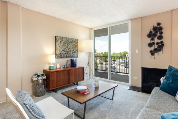 Beacon House apartment living room with plush carpet, fireplace, mid century modern furniture, and balcony door.