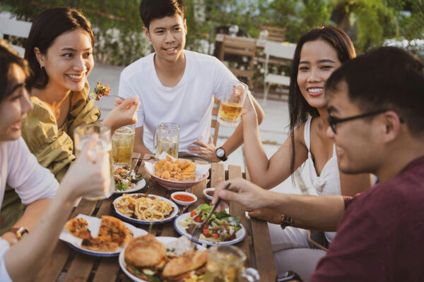 Friends at outdoor table enjoying food and drinks.