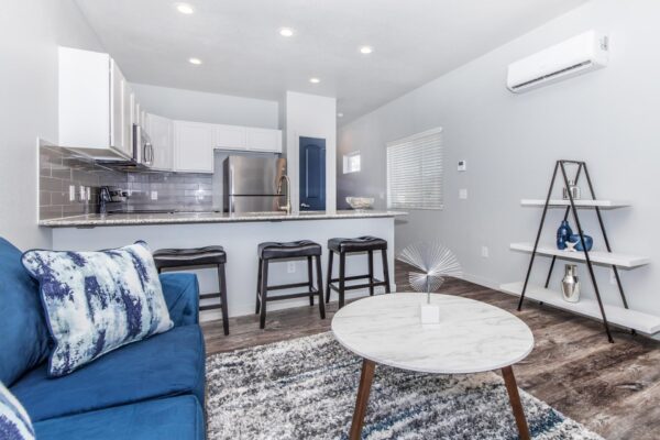 Cottages at Torin Point apartment living area with plush couch, breakfast bar with stools, and shelving unit.