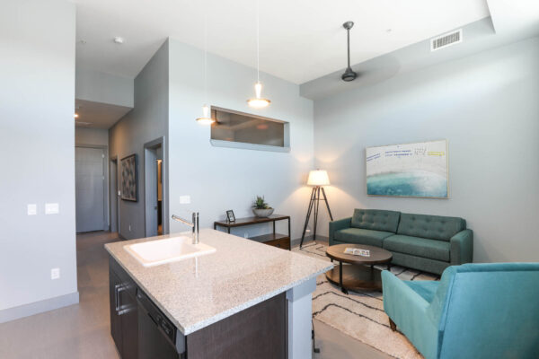 Forum Fitzsimons apartment living area with plush seating, breakfast bar, and ceiling fan.