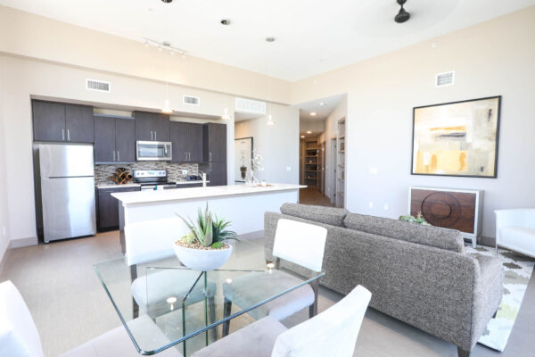 Forum Fitzsimons apartment living room with plush seating, elegant dining table, and large artwork.