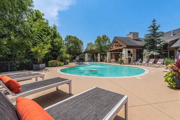 Highlands Lodge apartments pool area with lounge chairs, fountains, and lush landscaping.
