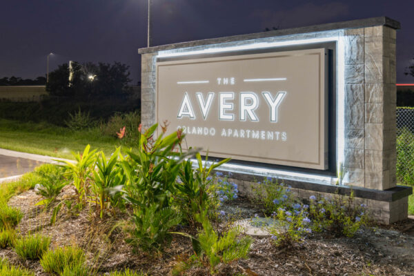 The Avery apartments signage with lush landscaping and flowers.