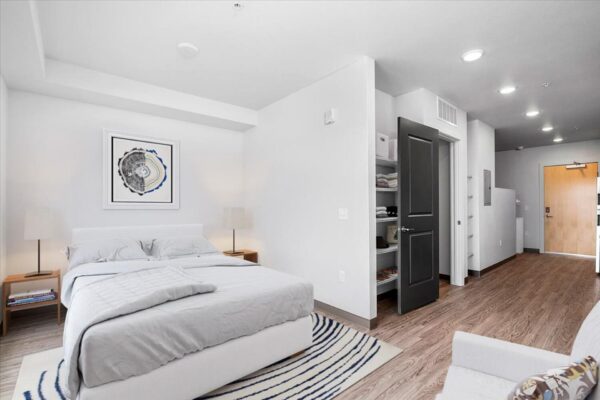 The Overland apartment living area with bed, couch, closet, and wall art.