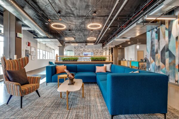The Overland apartments lounge with plush seating, colorful mural, and industrial styling.