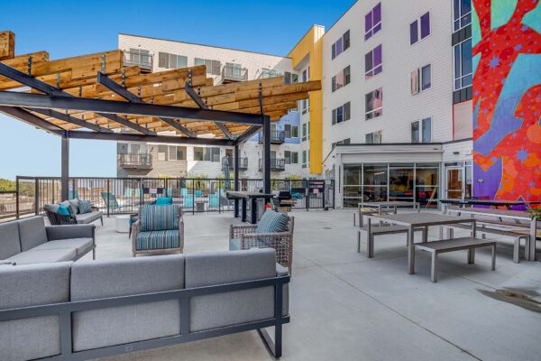The Overland apartments rooftop lounge with chairs, tables, pergola, and colorful mural.