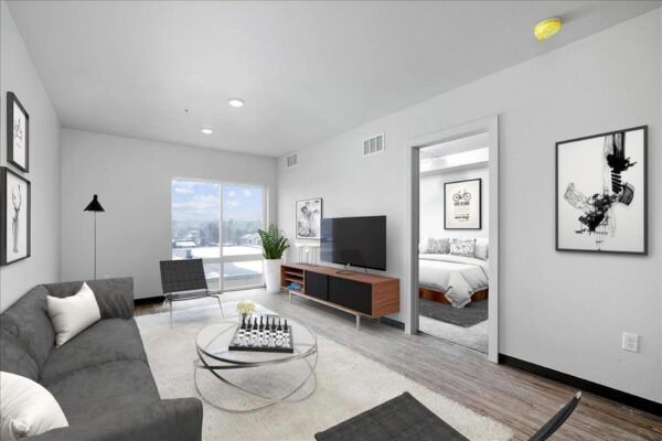 The Overland apartment living area with plush seating, console with TV, and large windows.