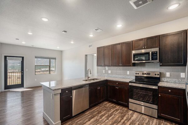 The Marc at Monument Ridge apartment kitchen with wood cabinets and stone counters.