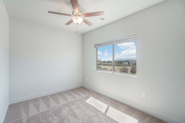 The Marc at Monument Ridge apartment bedroom with plush carpet, ceiling fan, and large window.
