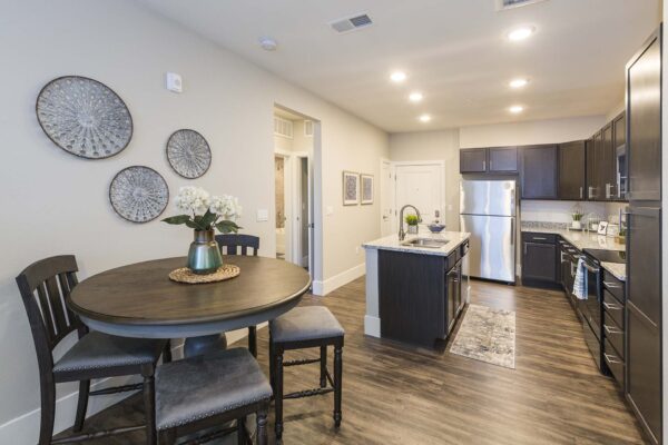 Retreat at Patriot Park apartment kitchen with wood style floor, wood cabinets, granite counters, and stainless steel appliances.