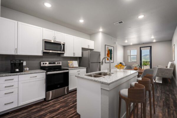 The Flats at Aero Park apartment kitchen with wood style floor, white cabinets, stone counters, and stainless steel appliances.