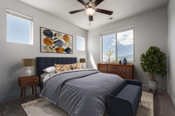 The Flats at Aero Park apartment bedroom with carpet, plush headboard, bedside tables with lamps, and ceiling fan.