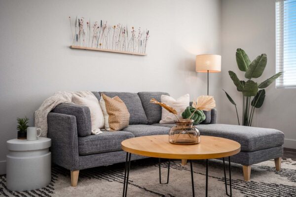 The Flats at Aero Park apartment living room with plush couch, table with decor, lamp, and large window.