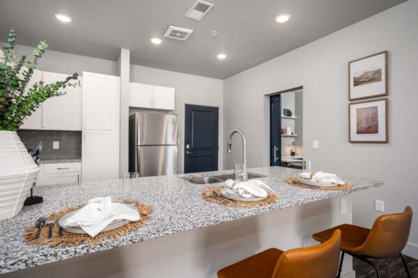 The Flats at Aero Park apartment kitchen with stone counters, breakfast bar with stools, and stainless steel appliances.