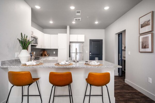 The Flats at Aero Park apartment kitchen with stone counters, breakfast bar with stools, and stainless steel appliances.