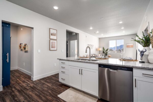 The Flats at Aero Park apartment kitchen with wood style floors, white cabinets, stone counters, and stainless steel appliances.