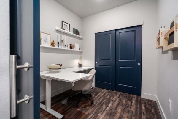 The Flats at Aero Park apartment office with wood style floor, desk, chair, and shelves with decor.