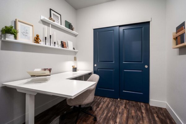 The Flats at Aero Park apartment office with wood style floor, desk, chair, and shelves with decor.