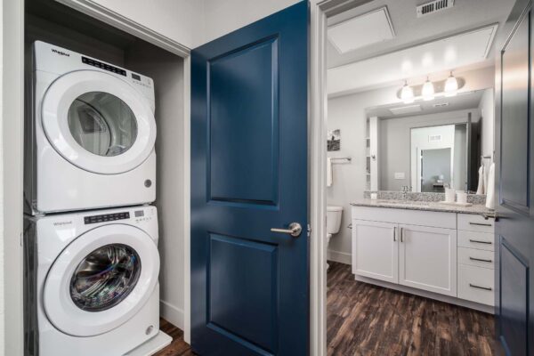 The Flats at Aero Park with wood style floors, bathroom, and laundry closet with stacked washer dryer.