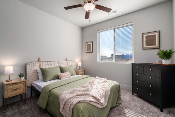 The Flats at Aero Park apartment bedroom with carpet, plush bed with headboard, and bedside tables with lamps.