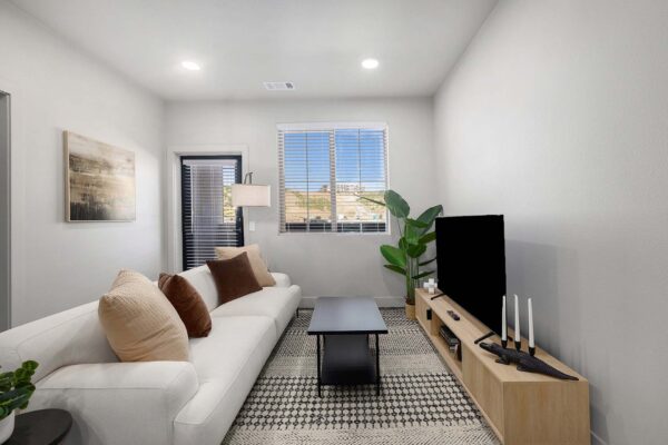 The Preserve at Mesa Creek apartment living room with plush couch, console with TV, and large window.