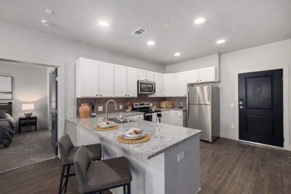 The Preserve at Mesa Creek apartment kitchen with wood style floor, stone counters, and stainless steel appliances.