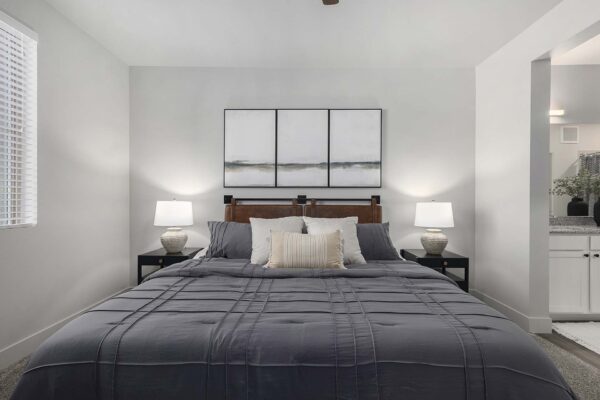 The Preserve at Mesa Creek apartment bedroom with plush bed, bedside tables with lamps, and framed artwork.