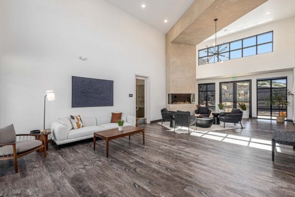 The Preserve at Mesa Creek clubroom with wood style floor, vaulted ceilings, plush seating, and fireplace.