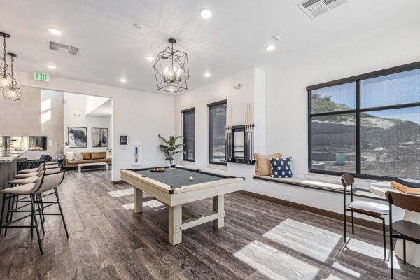 The Preserve at Mesa Creek game room with pool table, bench with pillows, and large windows.