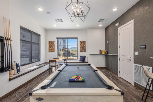 The Preserve at Mesa Creek game room with pool table, bench with pillows, and large windows.